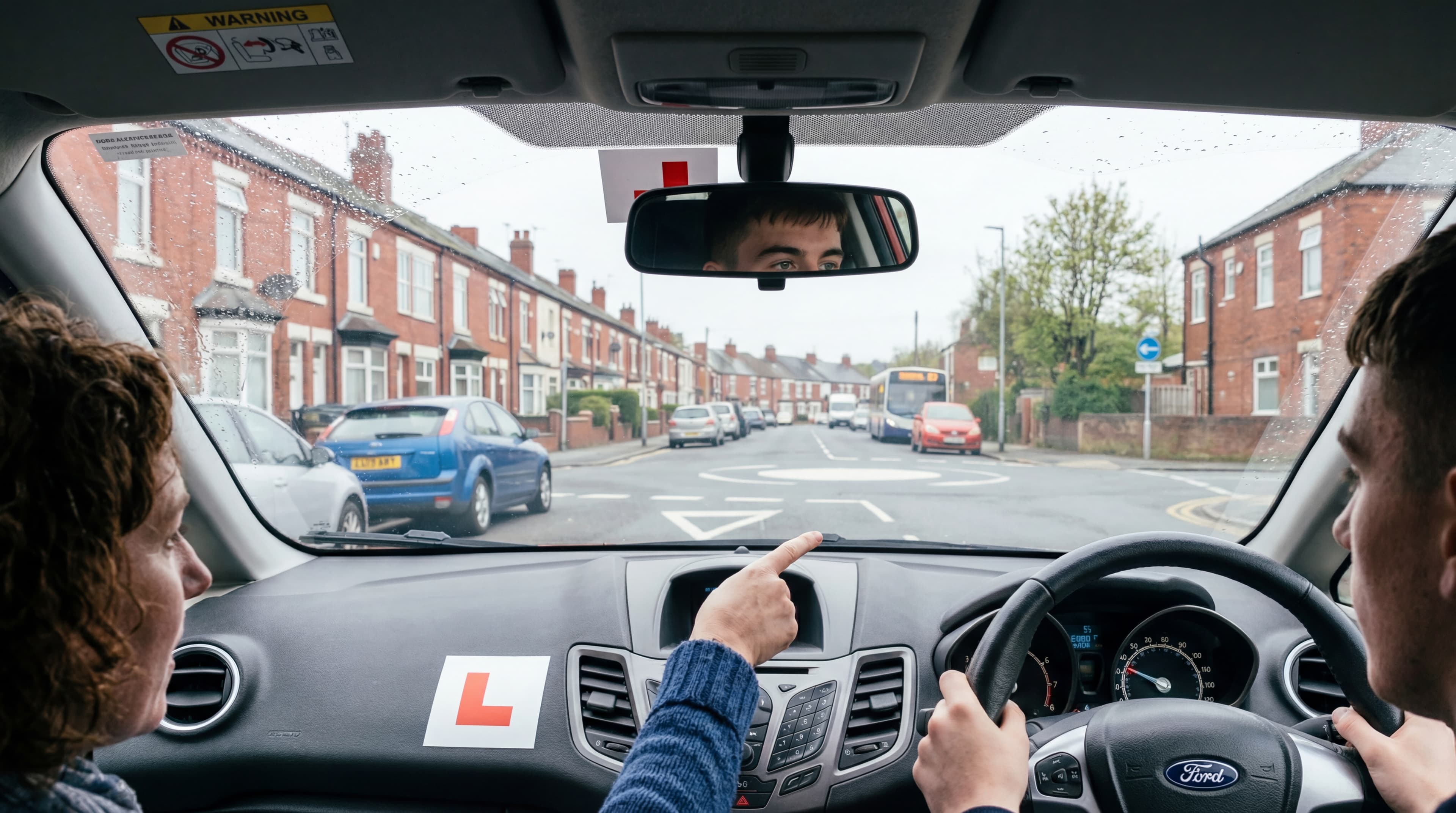 Learner driving on a UK residential street with instructor pointing at the road ahead